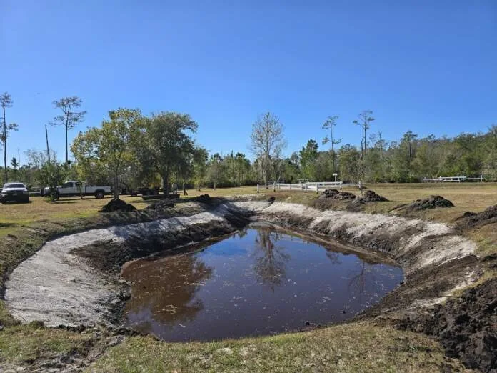 Excavator shaping a pond excavation on a DFCC Land Development project site.